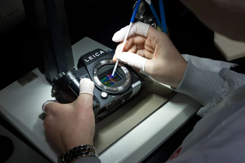 Precision cleaning of a Leica-SL3 lens using a cotton swab.