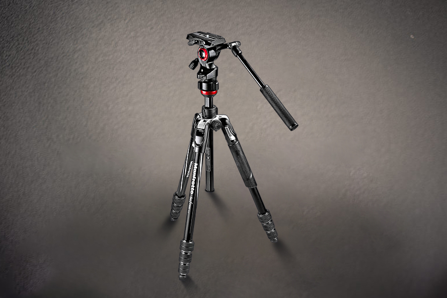 Black tripod with red accents standing on a textured surface, with one leg extended outwards.