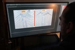 Man reviews garment design on a computer screen.
