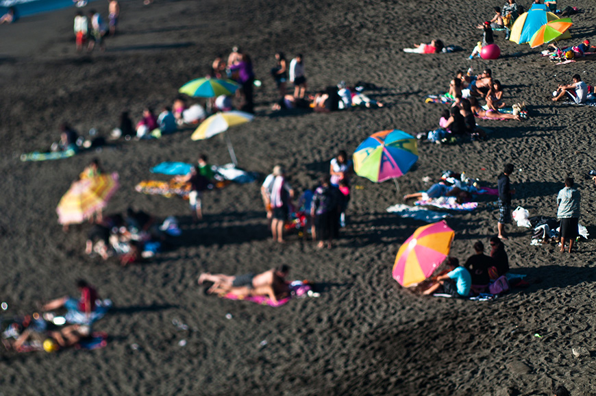 Beachgoers relaxing under colorful umbrellas on a sandy beach.