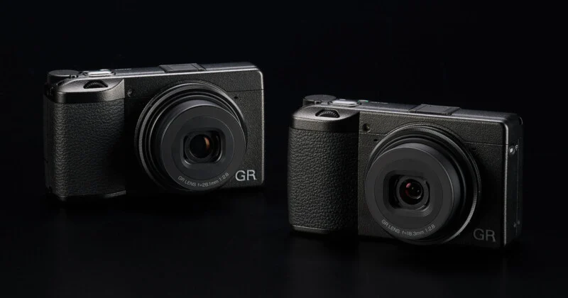 Two compact digital cameras against a dark background.