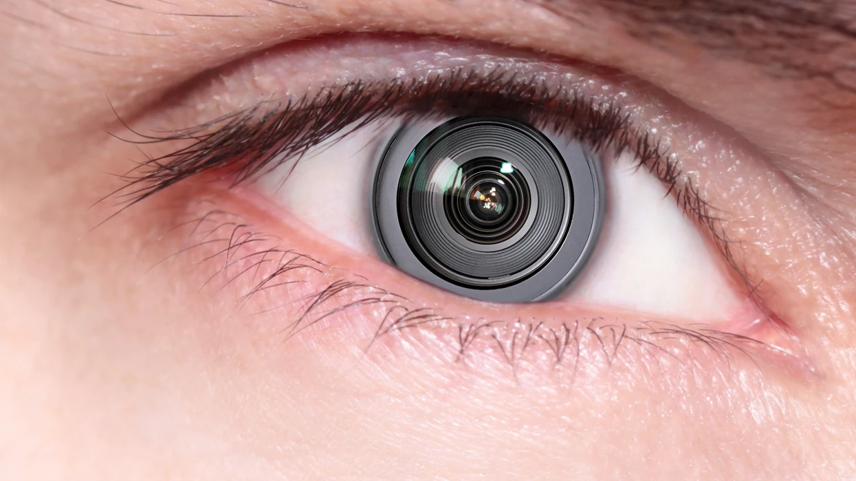 Close-up of a human eye with a camera lens for an iris, depicting a concept of surveillance or technology integration.
