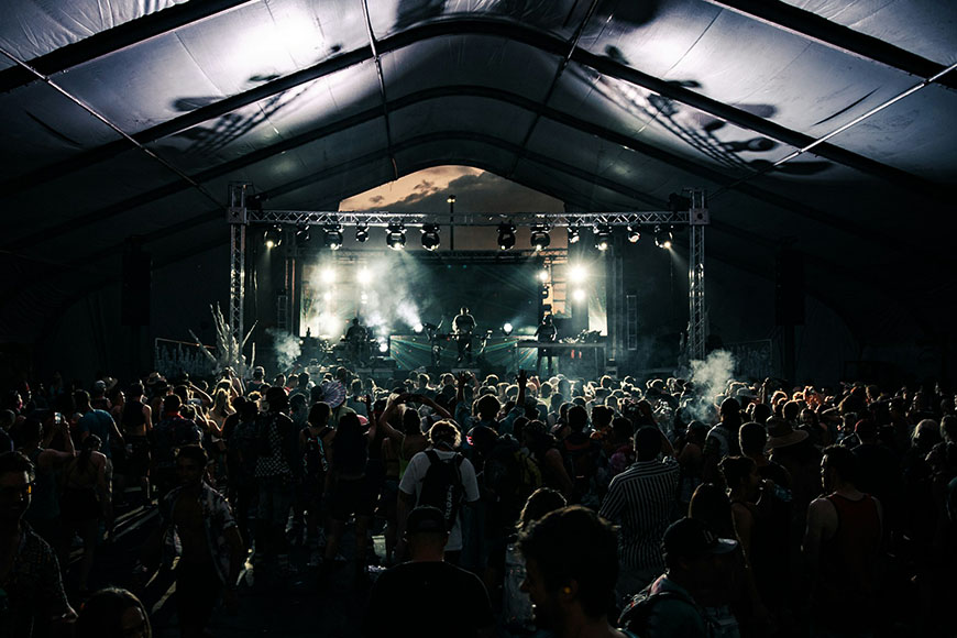 A crowd of people at a concert in a tent.