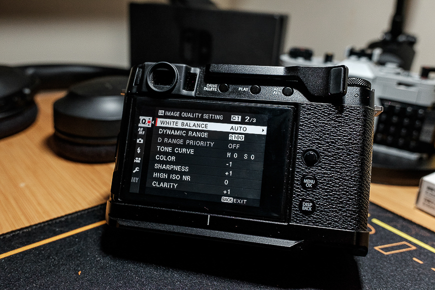 Digital camera with an open settings menu displayed on its lcd screen, situated on a desk.