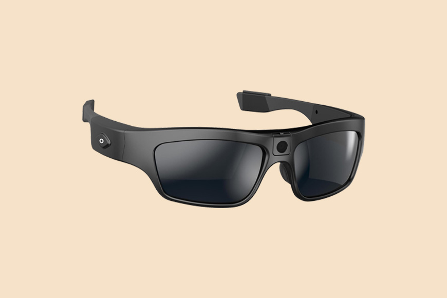 Black smart glasses with integrated camera and touchpad on a beige background.