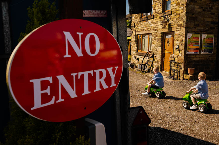 No entry" sign with two children riding toys in the background.
