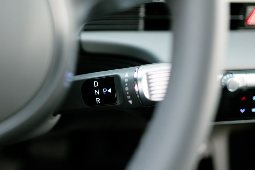 Automatic gear shift lever with drive modes showing through a car's steering wheel.
