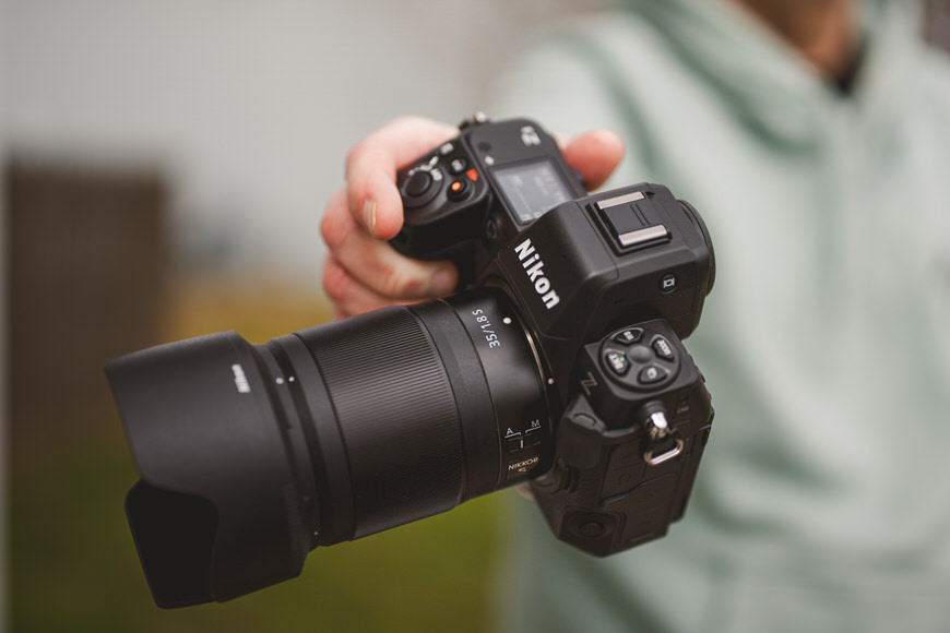 Person holding a nikon dslr camera with a long lens.
