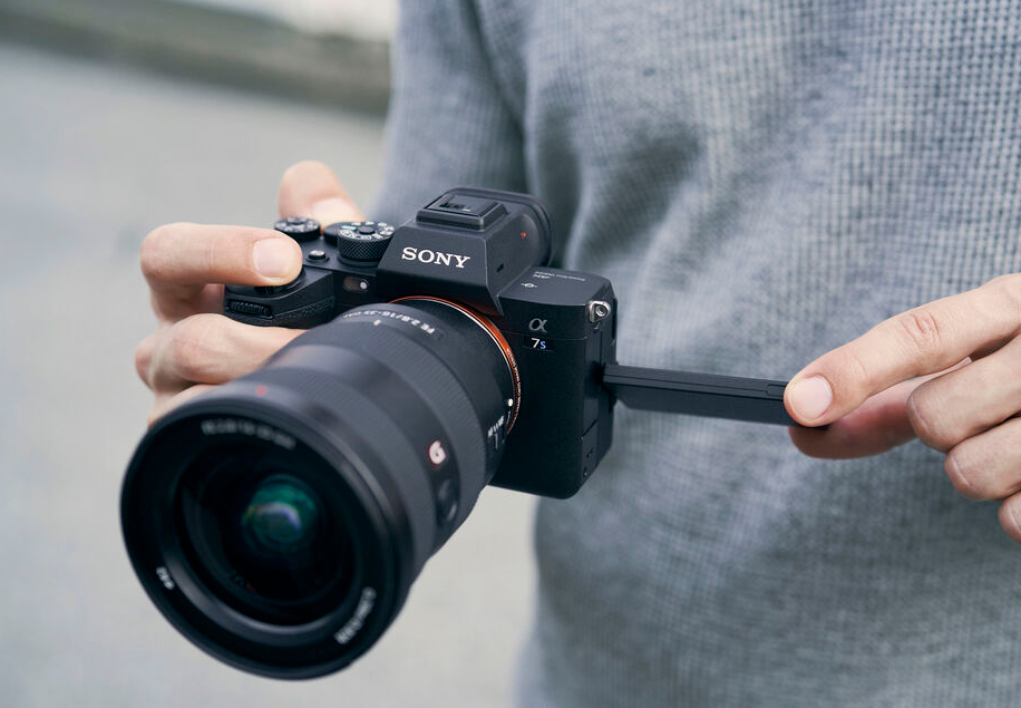 A person holding a sony mirrorless camera with a flip-out screen extended.