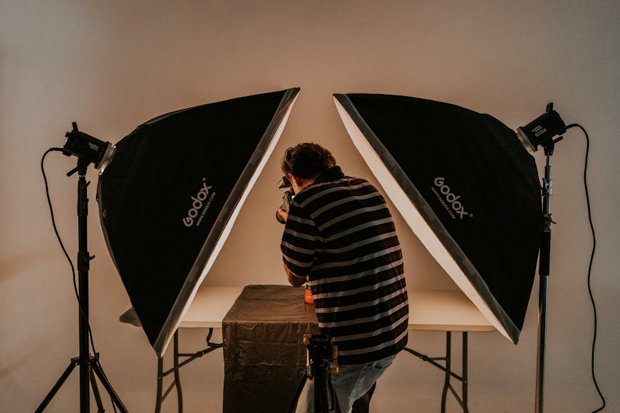 Photographer adjusting equipment between two large studio lights.