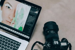 Digital photography workflow with a dslr camera beside a laptop displaying photo editing software.