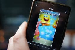 A person's hand holding a smartphone displaying an image of spongebob squarepants being edited in a photo application.
