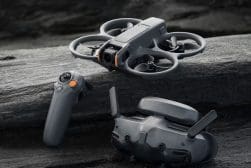 A compact grey drone with its controller and folded form, placed on a rough rocky surface.