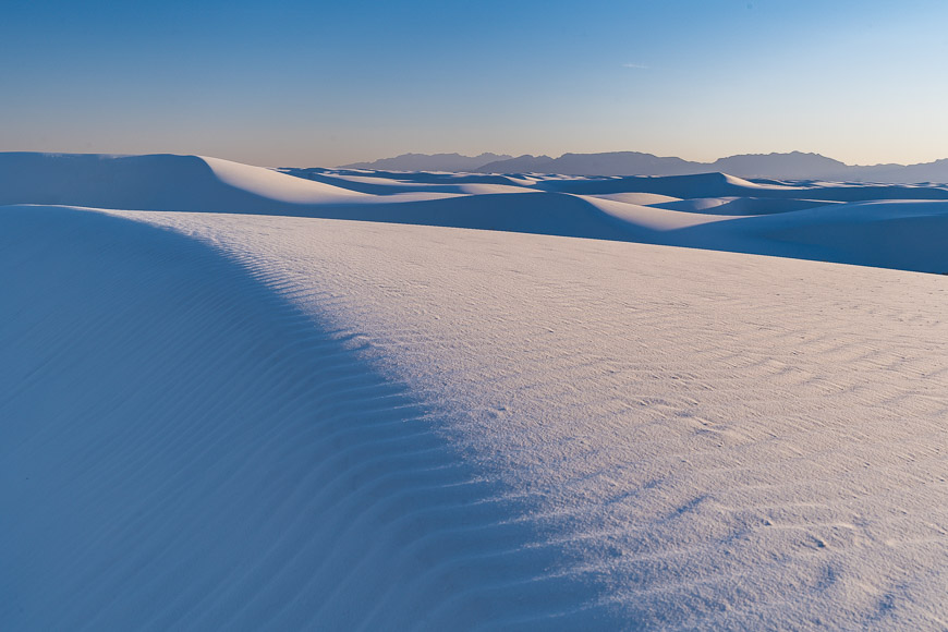 Gypsum sand dunes under a gradient sky at white sands national park, new mexico, near sunset.