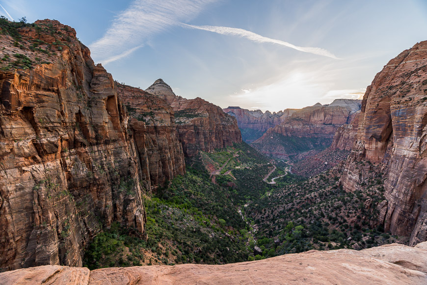 A panoramic view of a canyon with steep cliffs and a winding river at sunset.