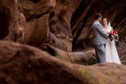 Bride and groom sharing a joyful moment in a rocky cavern.