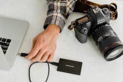 Photographer transferring images from a dslr camera to a laptop using an external ssd.