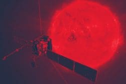 A spacecraft with solar panels orbits near the Sun, which glows intensely red and appears highly detailed.