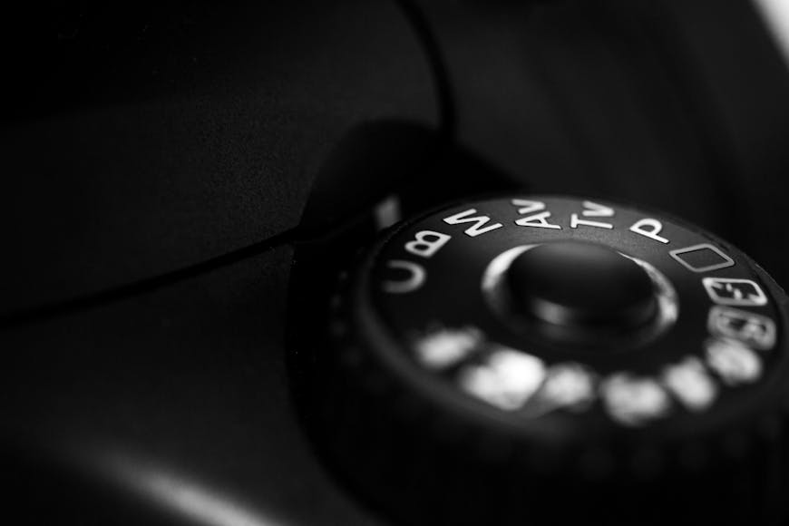 Close-up of a camera mode dial in monochrome, showing various settings like auto, p, s, a, and m.