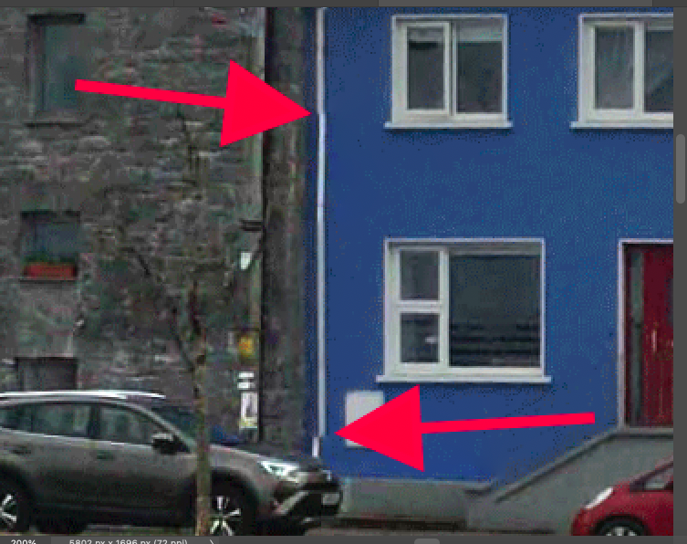 Two cars parked in front of a blue house.