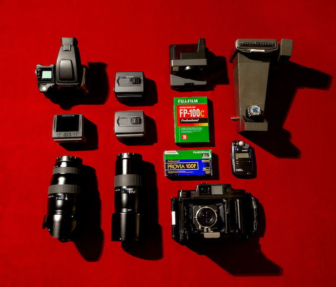 Assorted photography equipment neatly arranged on a red background.