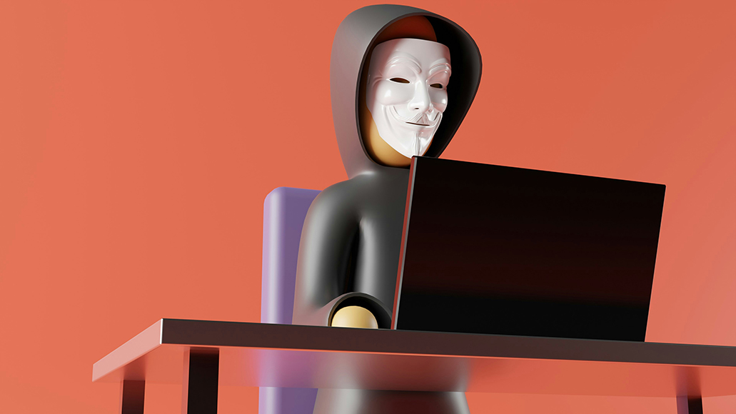 A person in a hooded sweatshirt and white mask sits at a desk using a laptop, against an orange background.