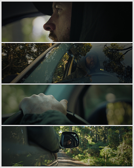 A man drives through a forest; close-ups show his face, hand on the steering wheel, and his reflection in the side mirror.