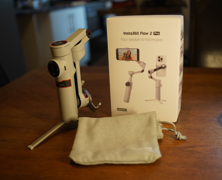 Insta360 Flow 2 Pro gimbal with tripod base, its product box, and a grey drawstring storage pouch.