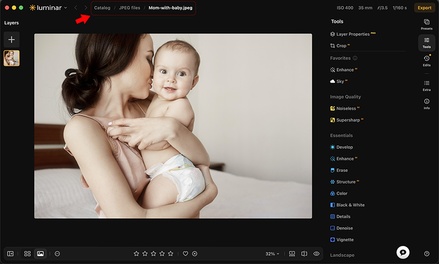 A woman in a beige top holds a baby in a diaper while standing indoors. The image is displayed on a photo editing software interface.