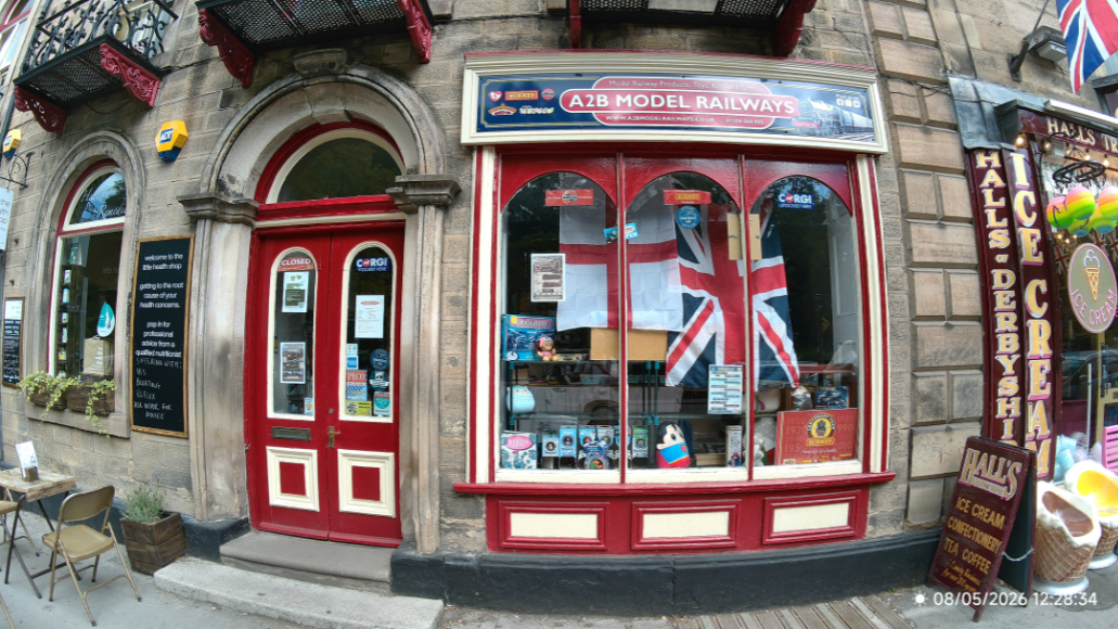 Storefront of A2B Model Railways with red window frames and a sign for Halls of Derby ice cream next door.