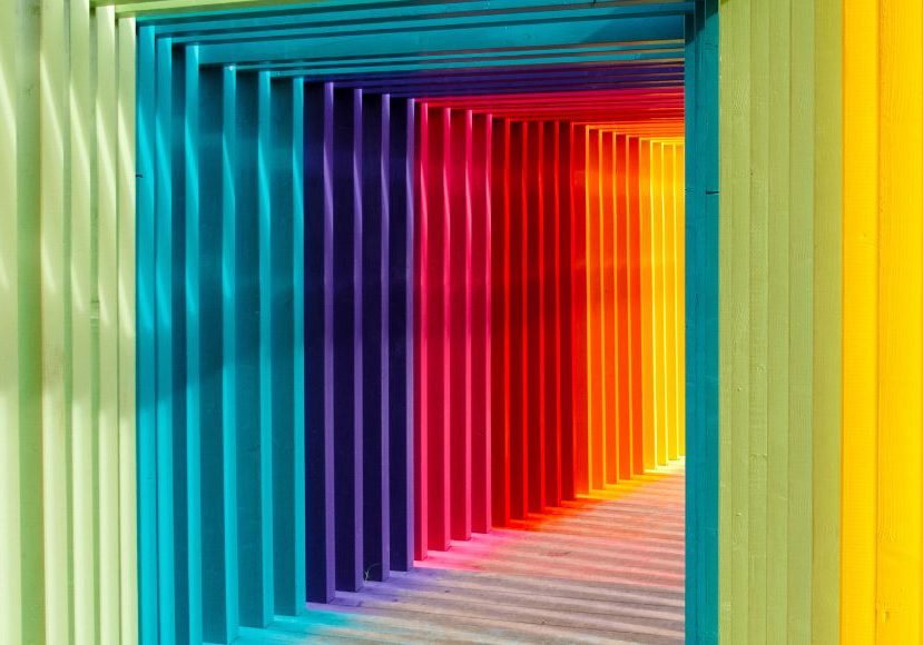A rainbow colored tunnel leading to a building.