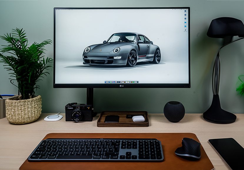 A desk with a monitor, keyboard, mouse and a car.
