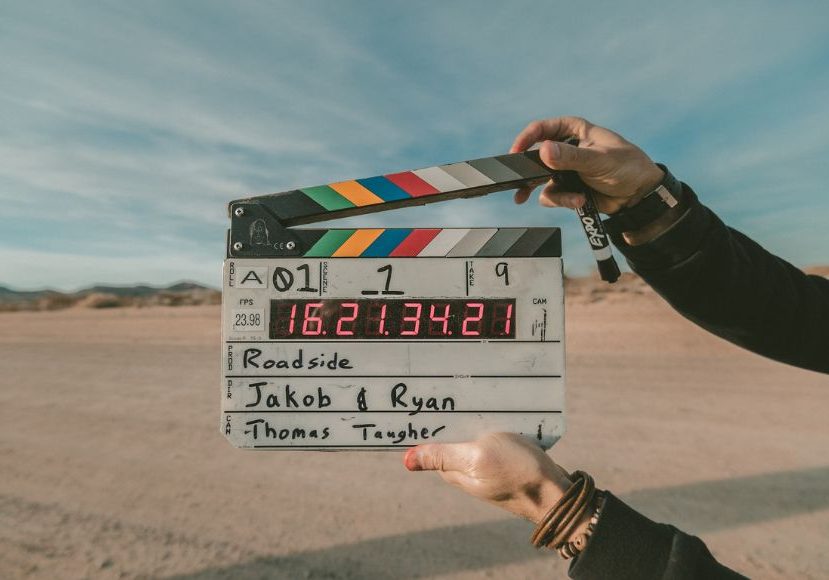 A person holding up a clapper board in the desert.