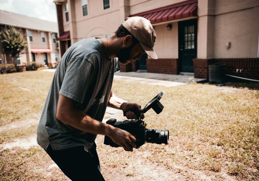 A man holding a camera in front of a building.