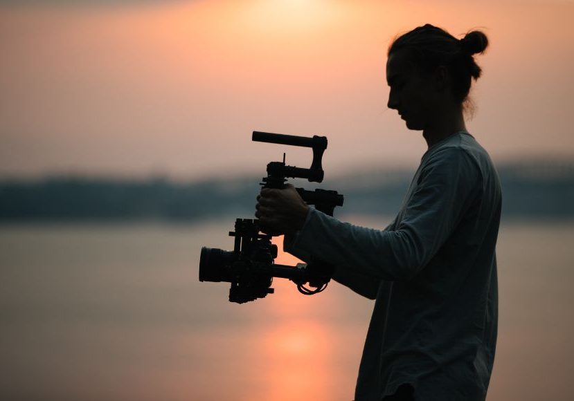 A man holding a camera at sunset.