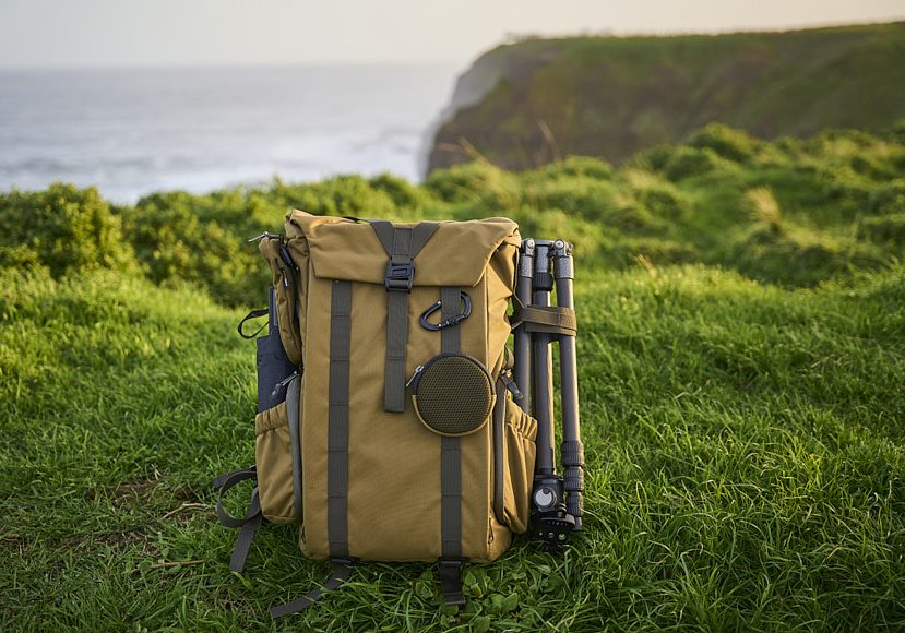 a backpack sits on a grassy field next to the ocean.