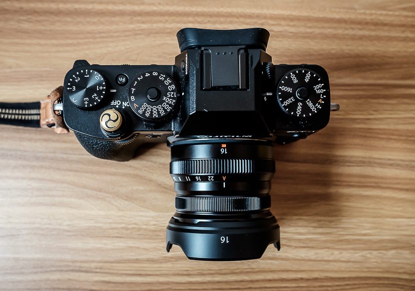 A top-down view of a mirrorless camera with a prime lens positioned on a wooden surface.