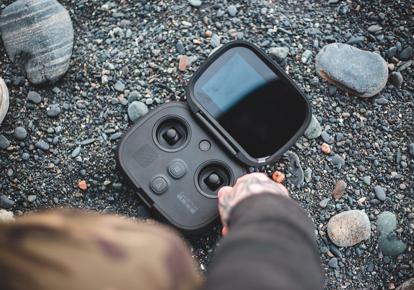 a person holding a black drone on a rock.