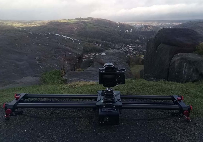 A camera sits on a slider in front of a mountain.