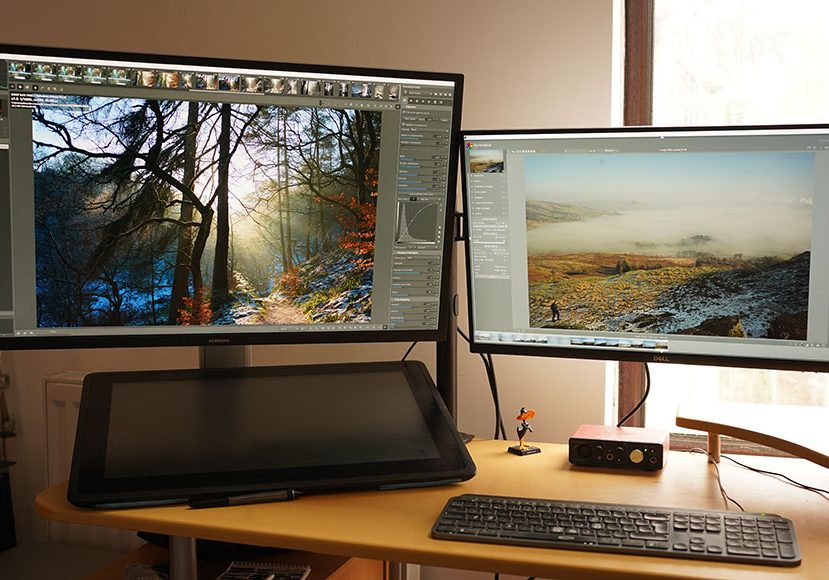 A desk with two monitors showing RawTherapee and Darktable software.