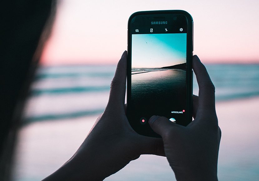 a person editing a photo of the beach with an Android cell phone.