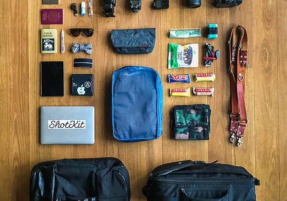 The contents of a travel bag are laid out on a wooden floor.