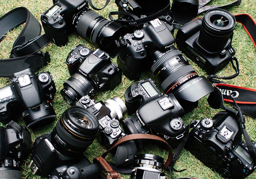 A group of cameras laying on the grass.