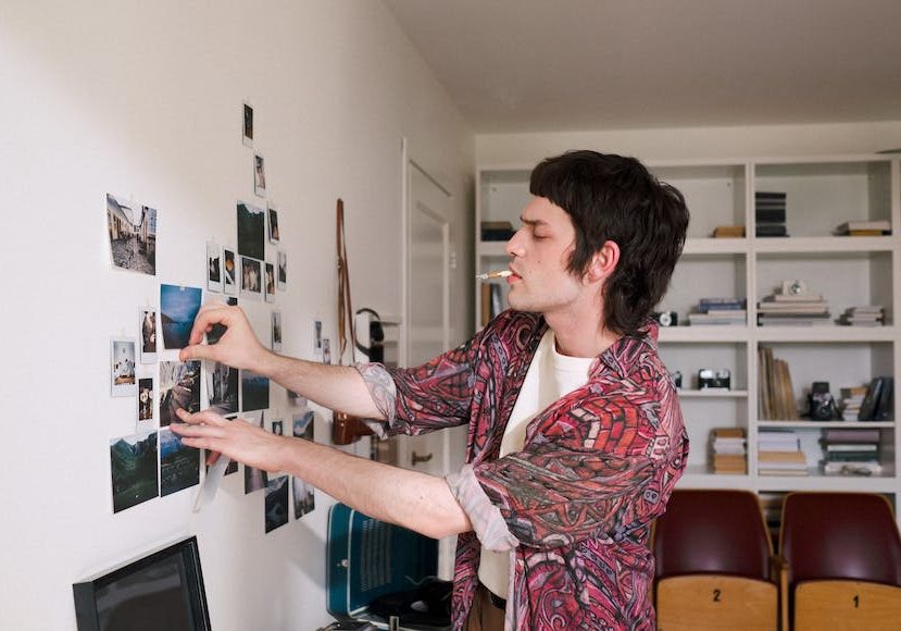 A man putting photos on a wall.