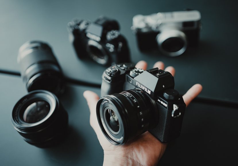 A person's hand holding several different cameras.