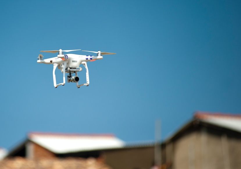 a white drone flying over a building.