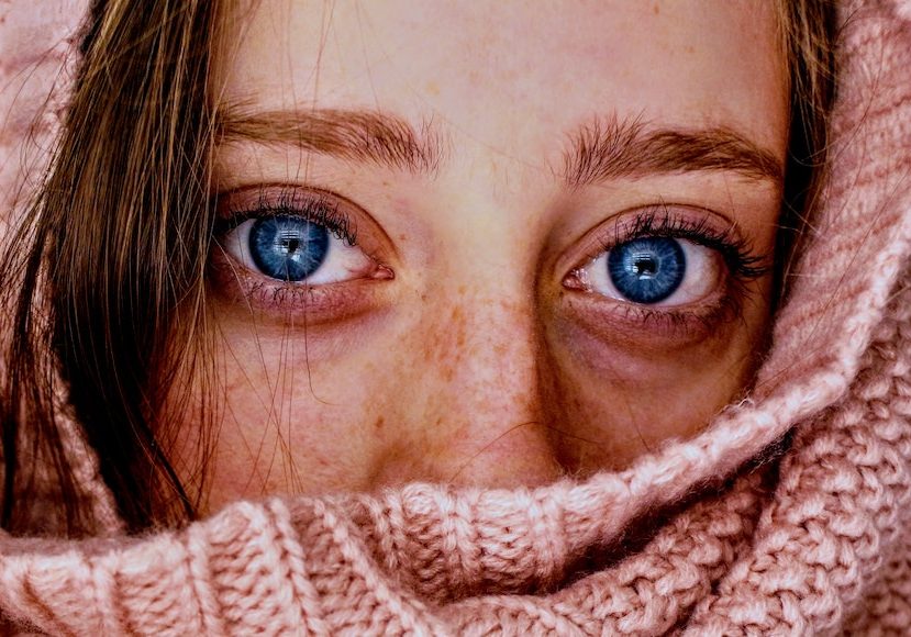 A woman with blue eyes covered in a pink scarf.