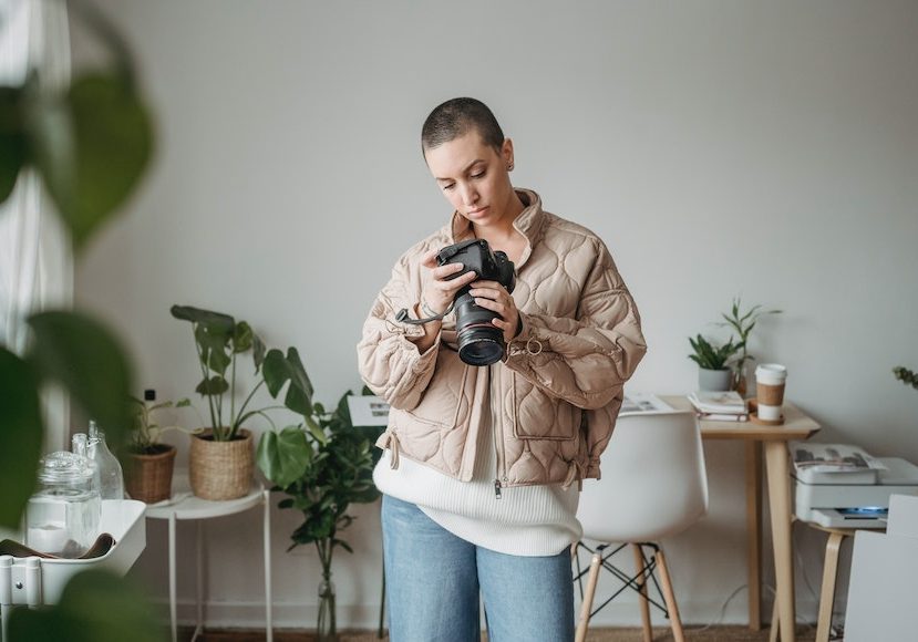 A woman holding a camera in her living room.