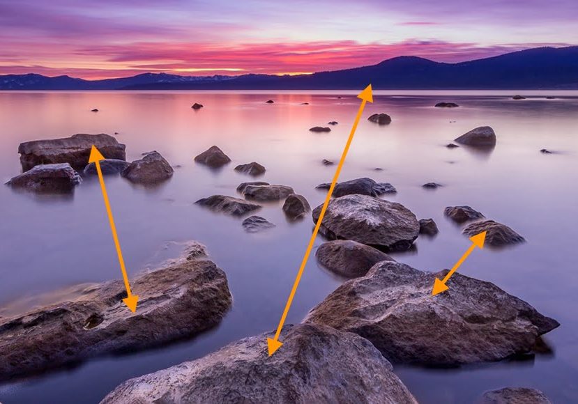 arrows pointing to rocks in the water at sunset.
