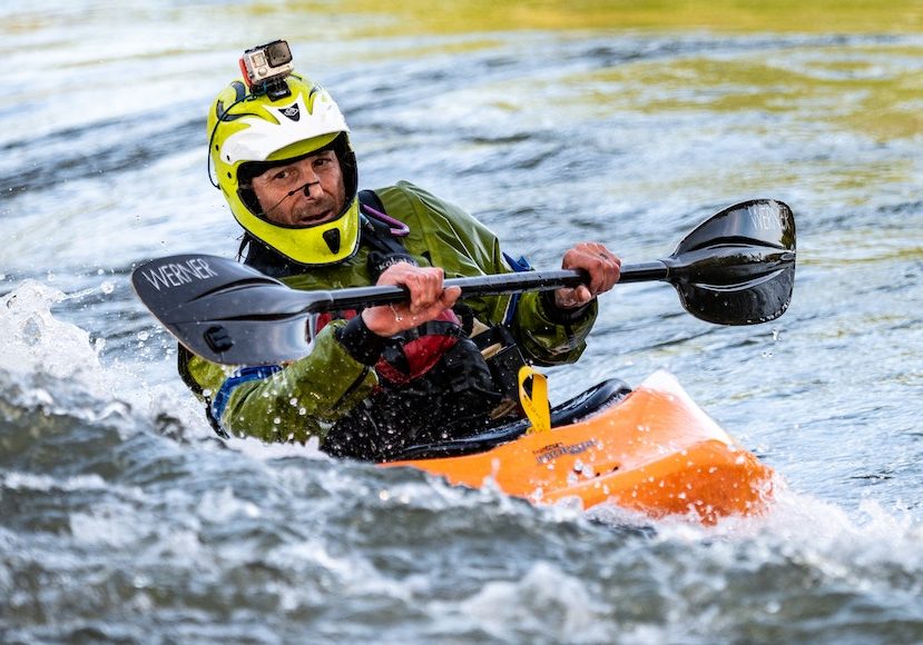 a man riding a kayak on top of a body of water with a go pro camera attached